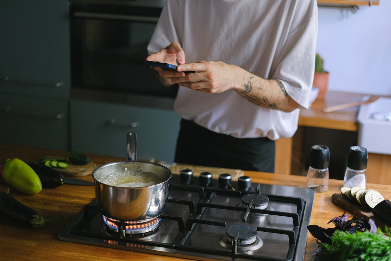services-03 A person takes pictures of a boiling pot on a stove, capturing culinary moments.