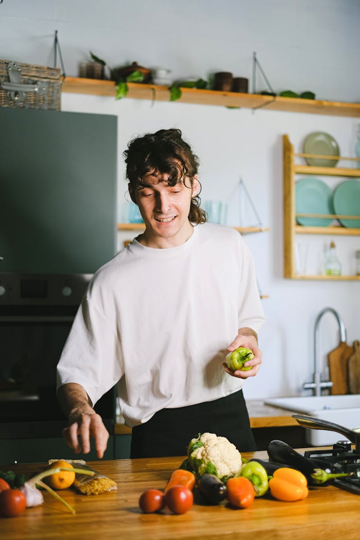 A young man preparing fresh vegetables in a modern kitchen setting, focusing on healthy cooking.
