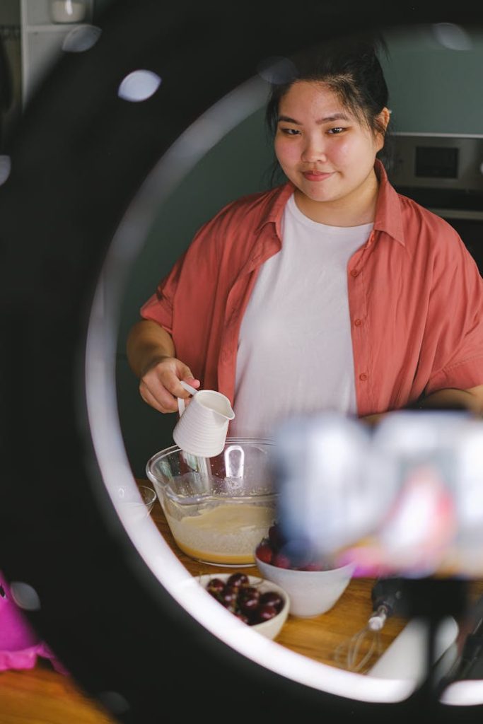 pexels photo 12674085 An Asian woman joyfully prepares food in a kitchen, surrounded by ingredients and kitchen tools.